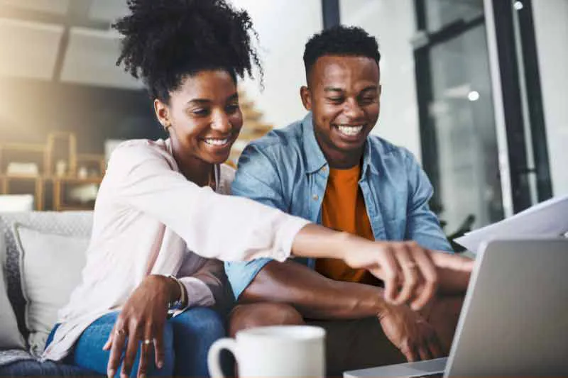 Happy couple pointing at laptop, discovering the best tax deductions and credits to maximize their refund.
