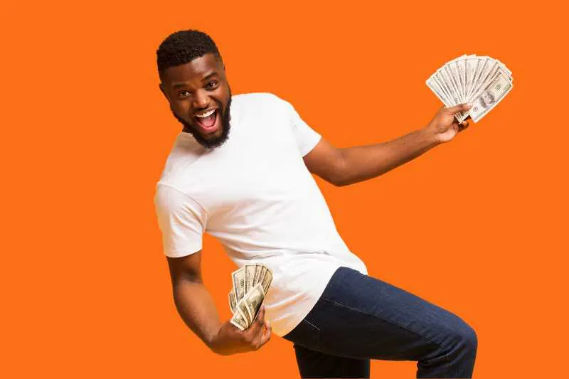 Happy man dancing with money in his hands, celebrating a fast tax refund after using tips for quick processing and faster returns.