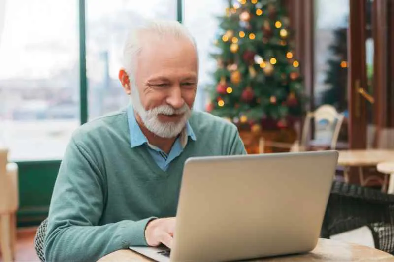 Senior man reviewing tax documents on his laptop, preparing for year-end tax planning and making moves before the New Year.