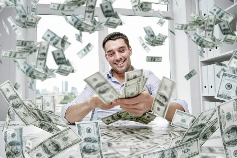 Man surrounded by money, excited about how to get a big tax refund by maximizing deductions and credits.