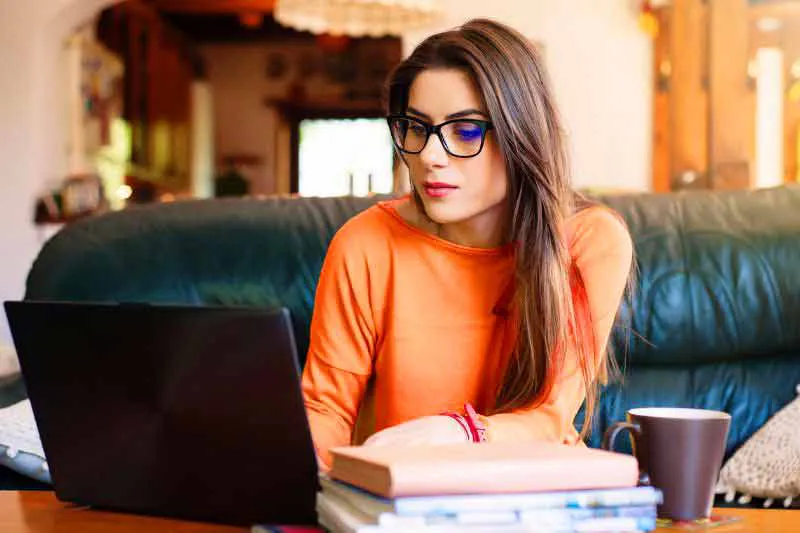 Woman looking at her laptop, considering the pros and cons of filing a tax extension for her federal tax return.