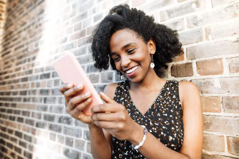 Happy woman looking at her phone and reviewing 2024-2025 tax brackets and federal income tax rates online.